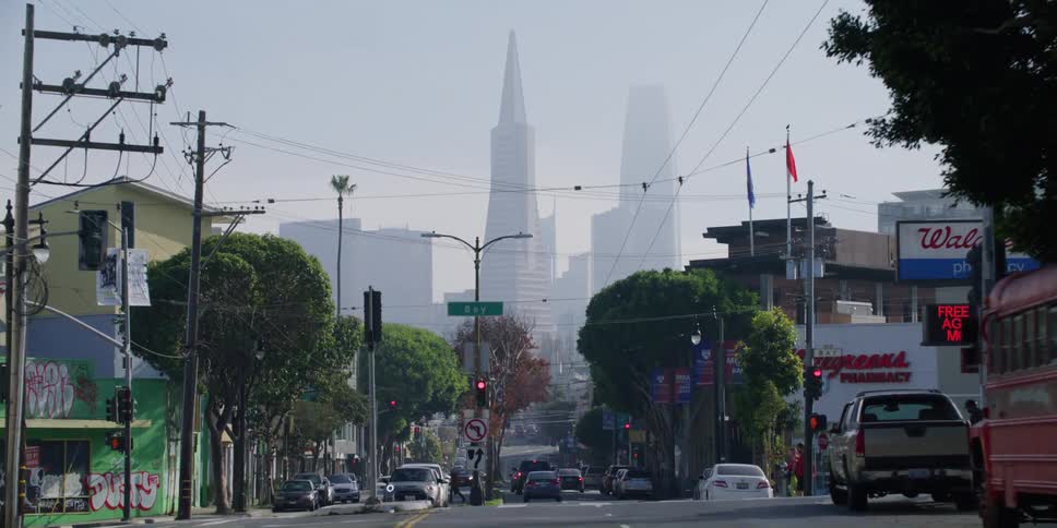 A city skyline is visible at the end of a main street with stores and homes