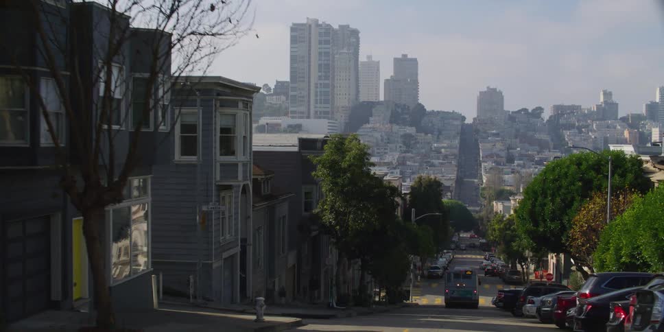 Steep street of an inner city neighborhood with multiple parked cars