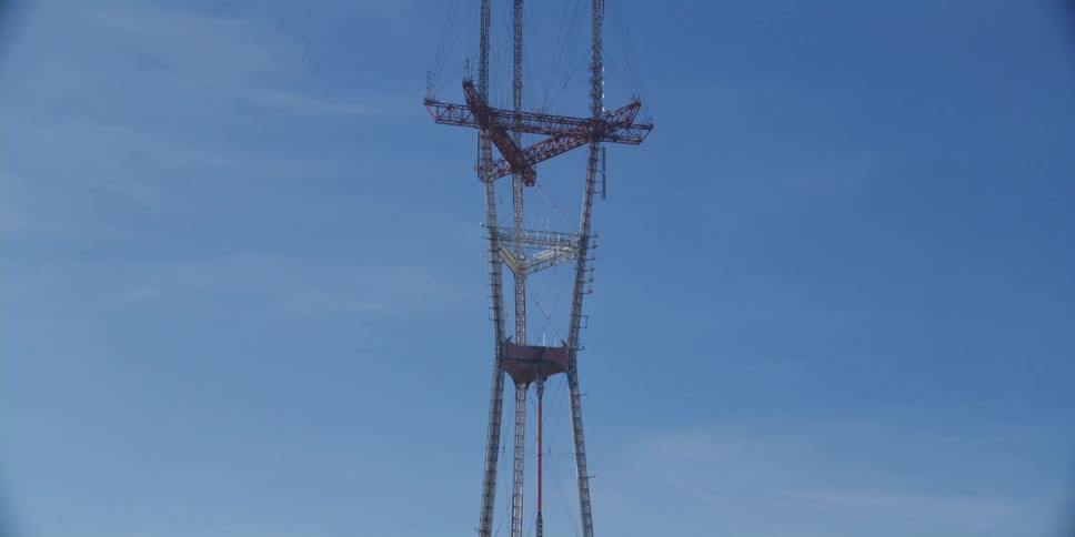A utility tower stands high in a blue sky