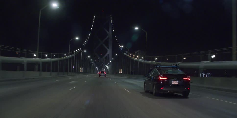 Automobiles traveling on a road at night pass through a well lit a tunnel