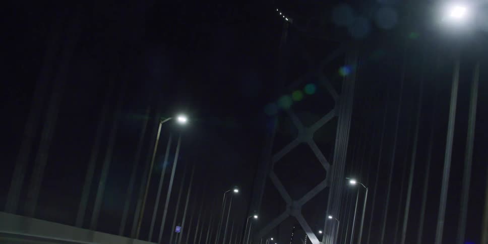 Vehicle crosses suspension bridge at night