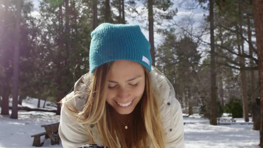 A smiling woman blowing snow from her hand