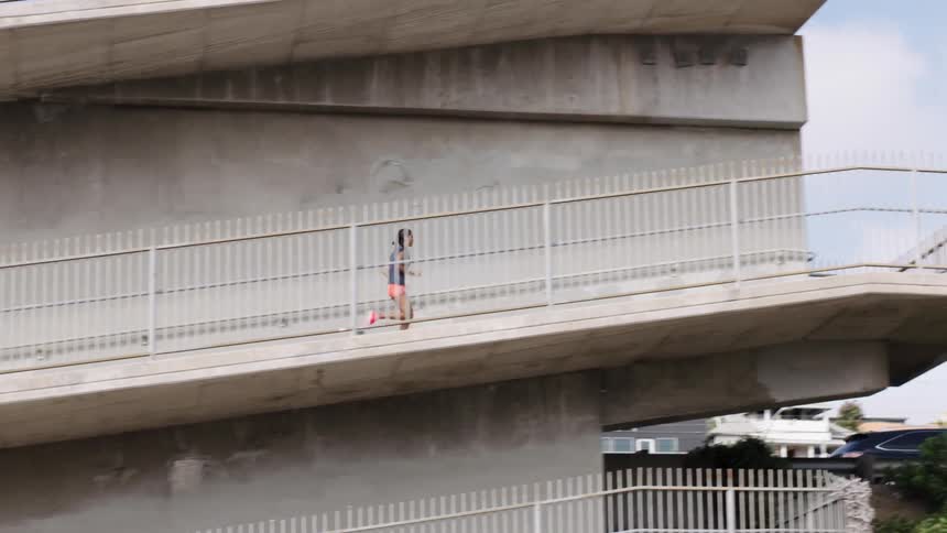 Woman jogging up an elevated footbridge