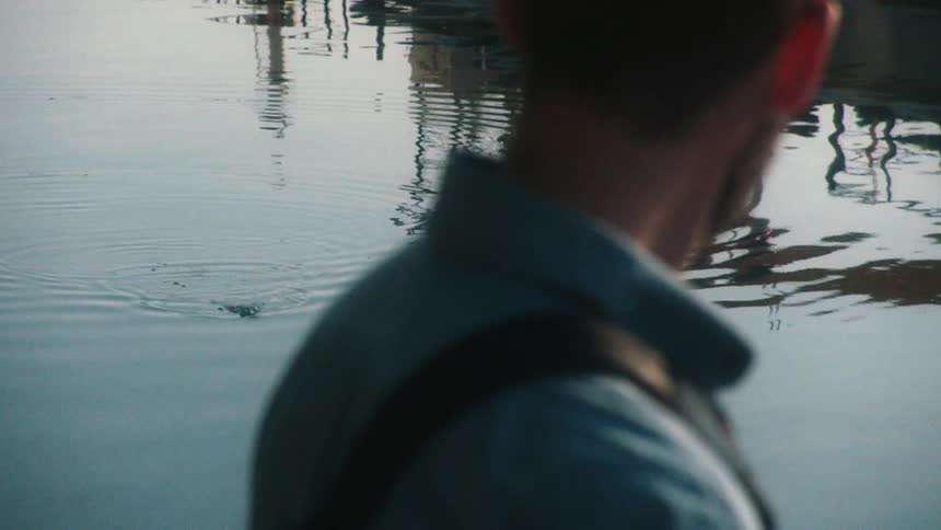 A man is standing outdoors near a body of water
