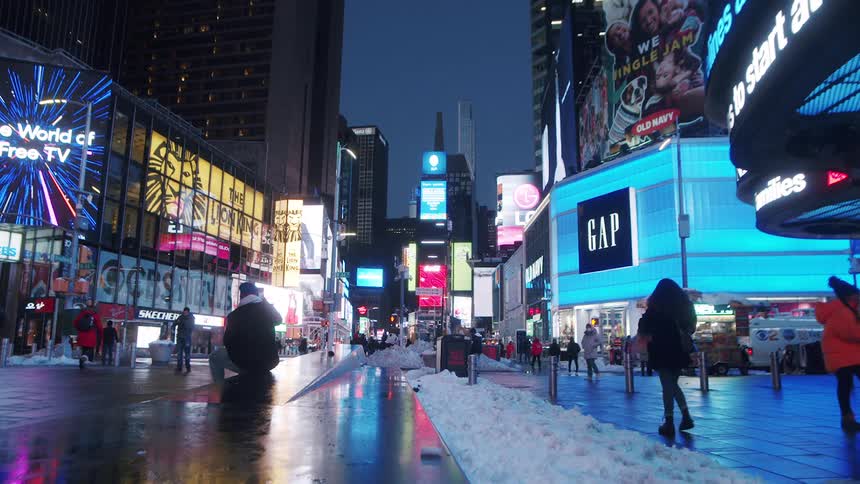 Night lights and billboards illuminate the people walking on broadway in new york city at night