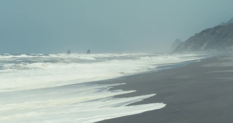 Foamy ocean waves break against the beach