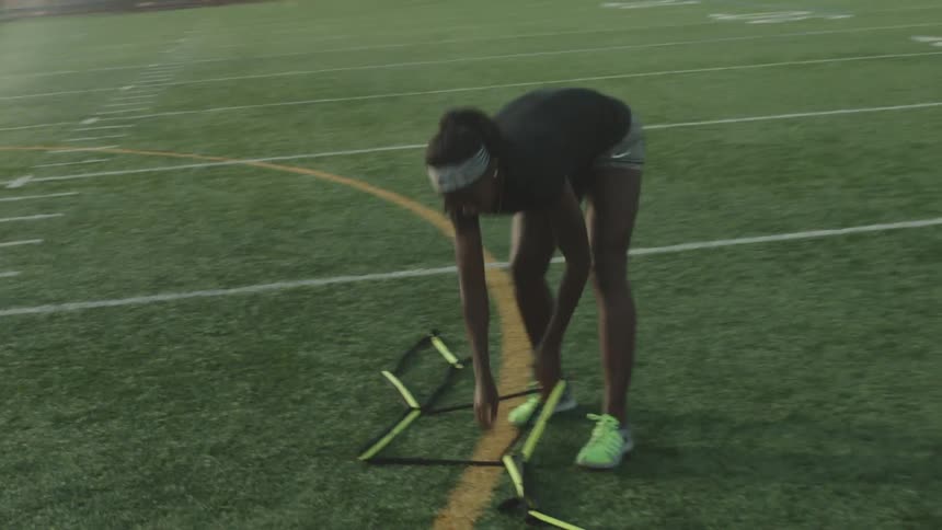 A woman unwinds something on a football field