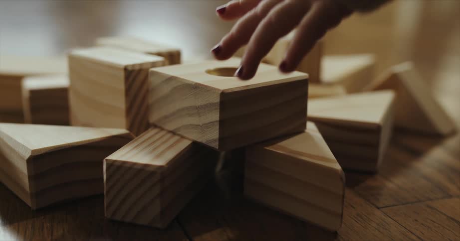 A child is picking up toy blocks