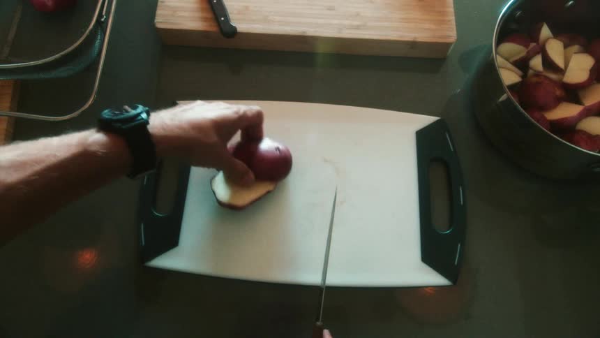 Overhead view closeup of man cutting red potatoes on a white cutting board