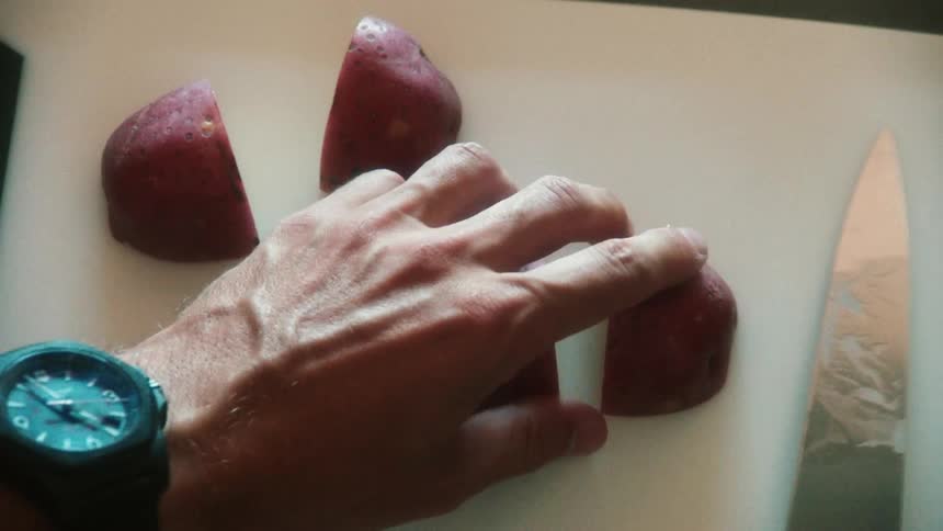 A man is cutting a potato with a knife