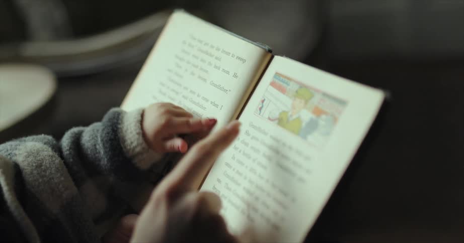 Mother reading a story from a book to her baby at home