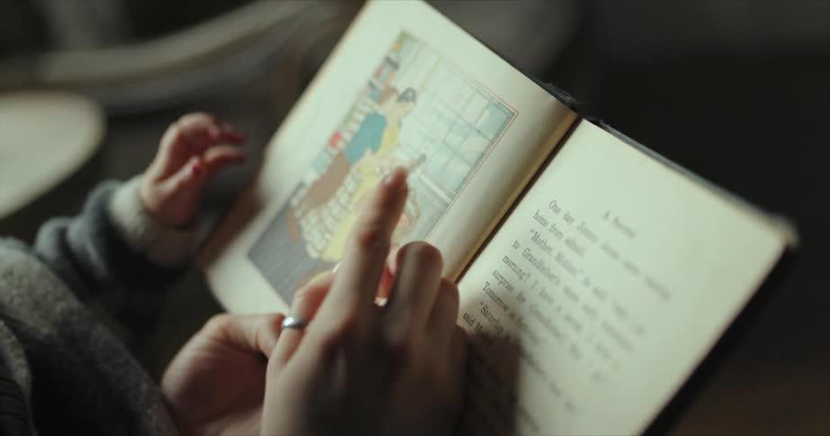 Mother reading a story from a book to her baby at home