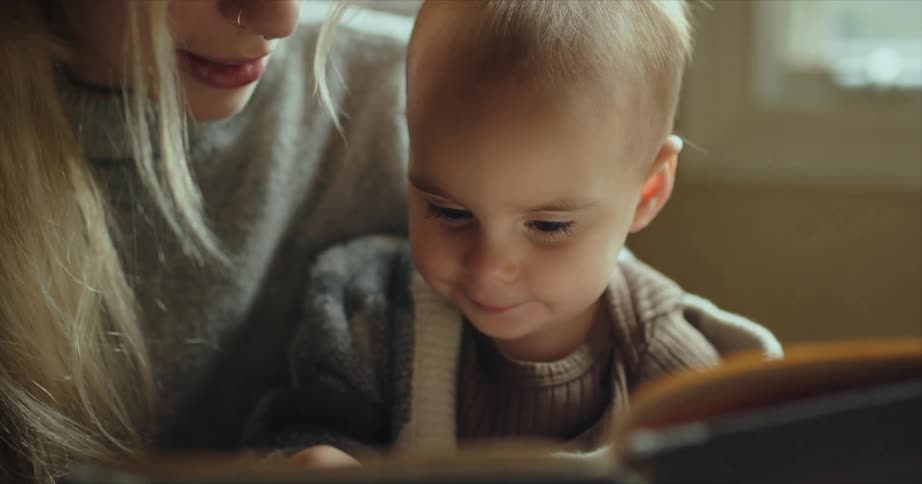 Mother reading a story from a book to her baby at home