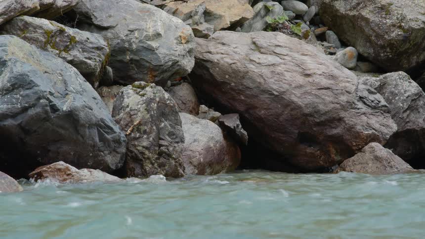 River flowing close to the big boulders on the riverbank at daytime