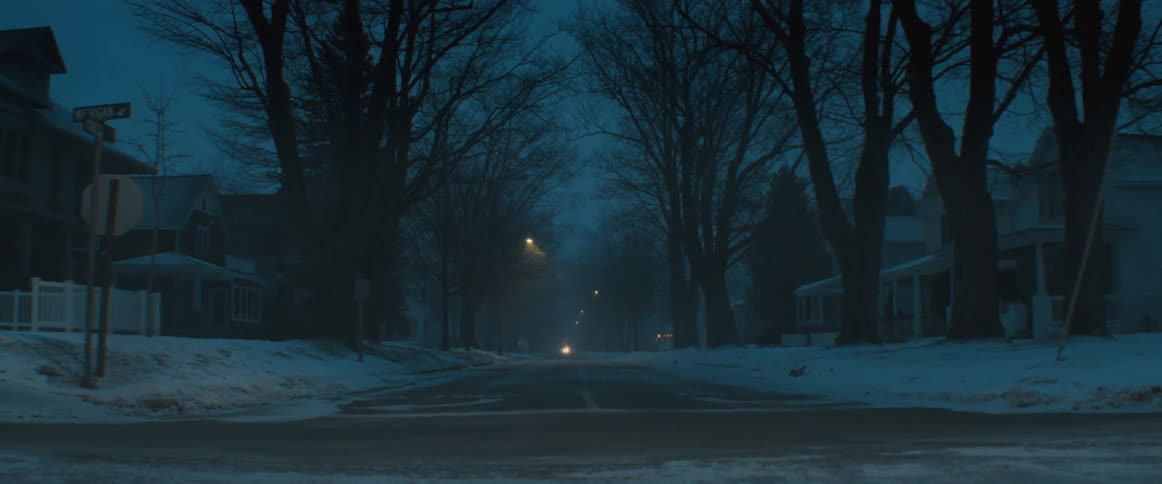 A view of a street in a neighborhood with snow