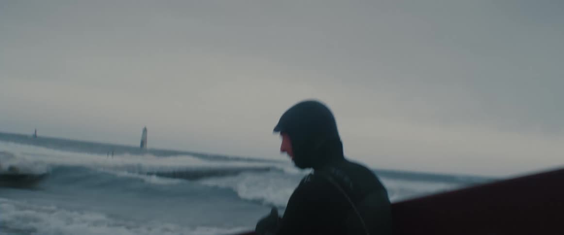 A man is jogging on the beach at dusk