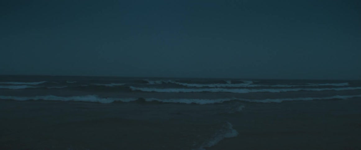 Ocean waves break agains the shore at dusk