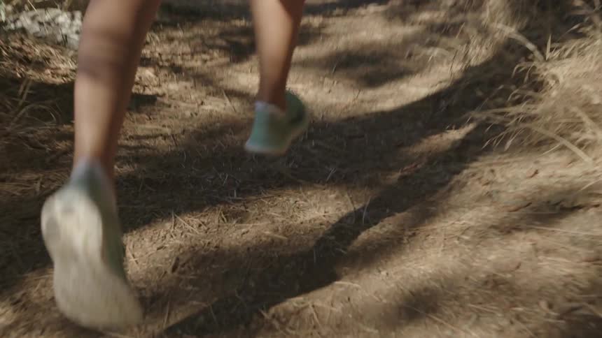 A woman jogs on a dirt path near a body of water