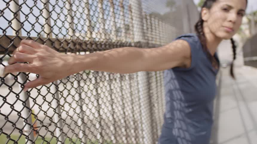 A woman holds onto the chain link fence of the highway overpass