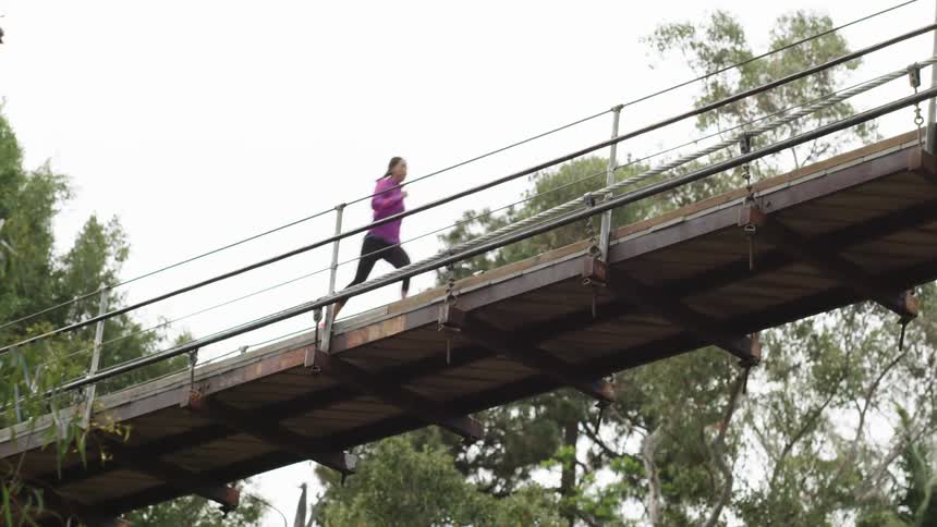 A woman running across a rickety bridge