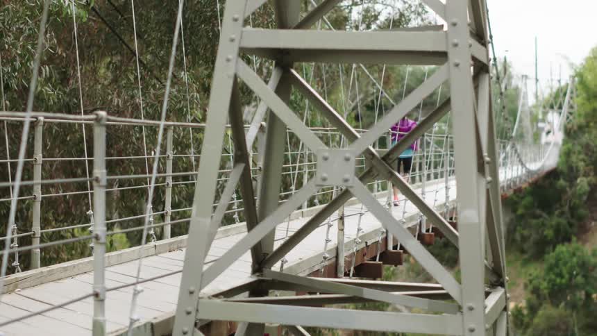Woman jogging across a foot bridge