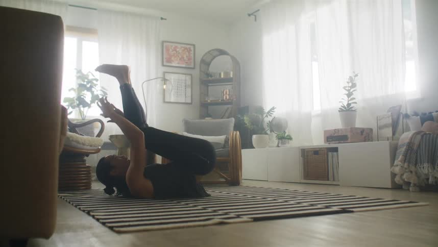 A man is on his back on the floor doing stomach exercises during the daytime at home