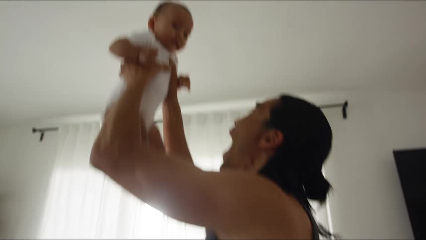 Father making dancing movies and lifting up his baby son from the floor while laughing