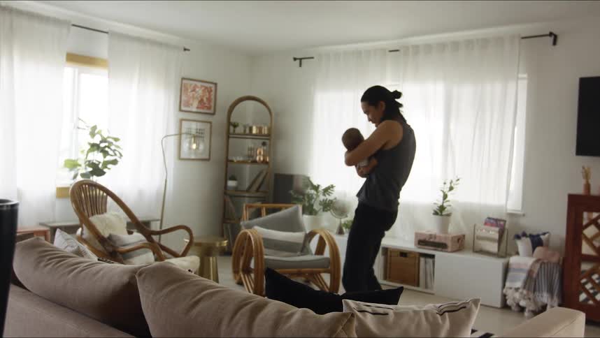 A man smiles and kisses his baby as he dances while holding him in the living room