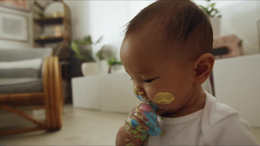 The baby is eating the finger paint