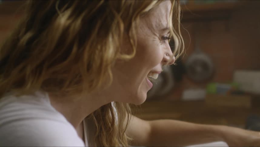 A woman is sitting in a kitchen and smiling