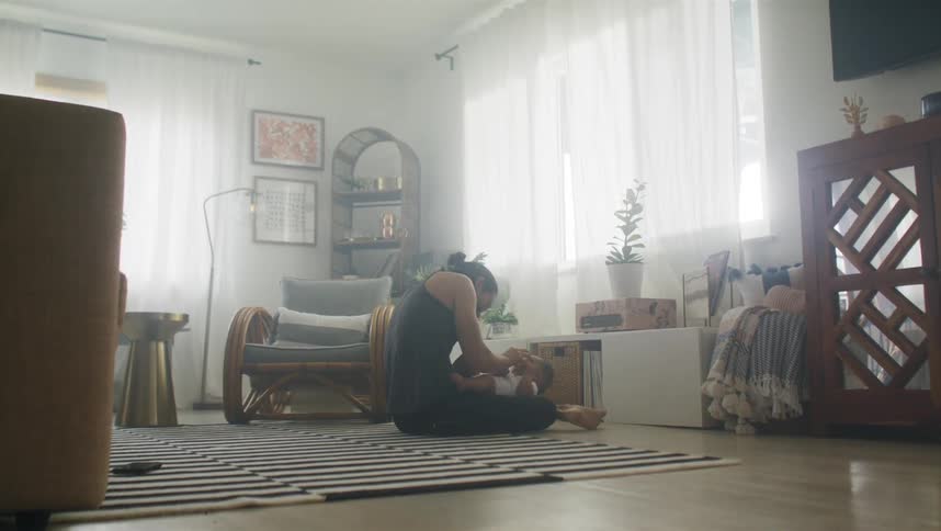 A man lies on his back and holds his son up with his feet