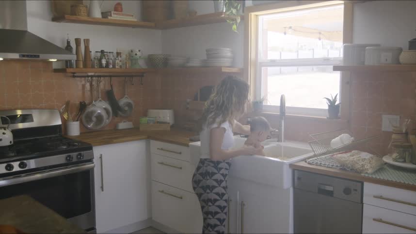 A mother baths her son in the sink