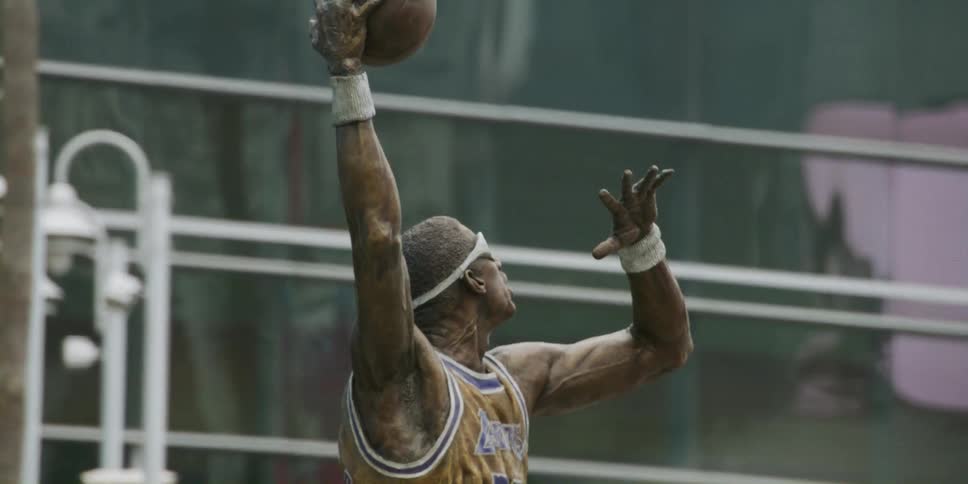 A statue of a basketball player next to a stadium