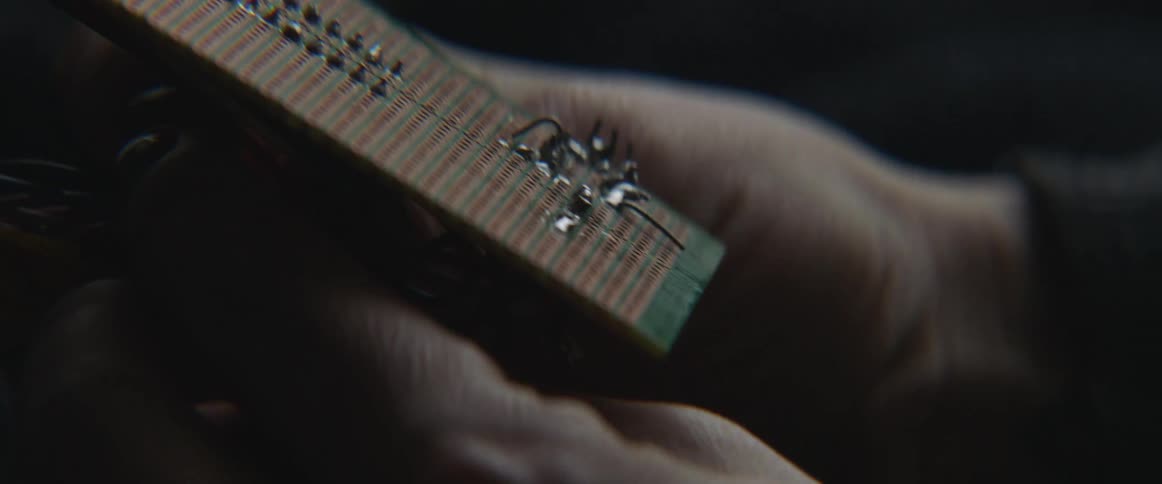 A person is holding a panel connected to wires