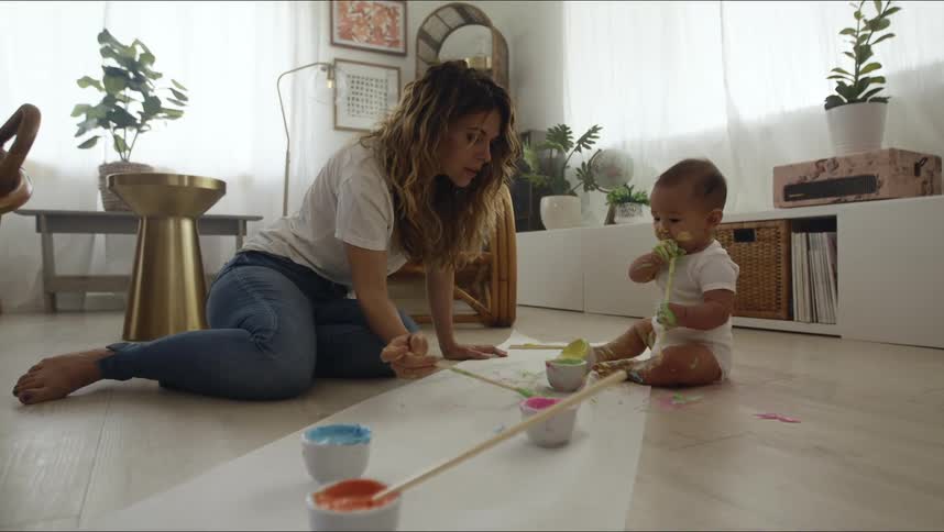 Mother and baby sitting on hardwood floor painting on butcher block paper