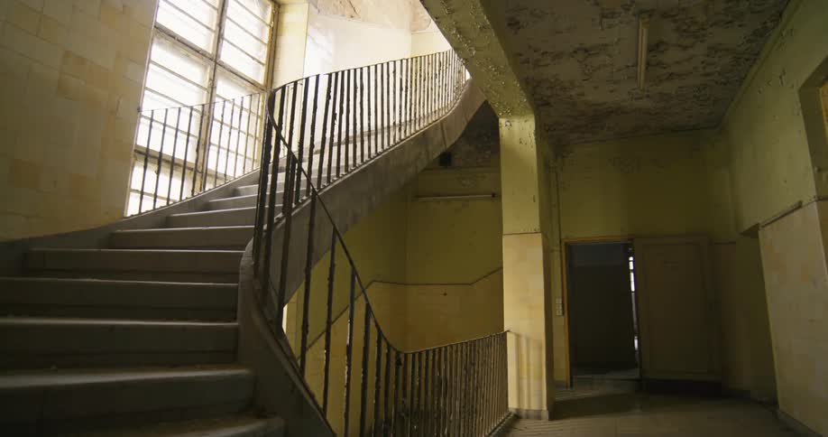 A curved staircase inside a vacant dilapidated building