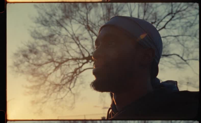 A young man stares off into the distance with the sun partially up and shining