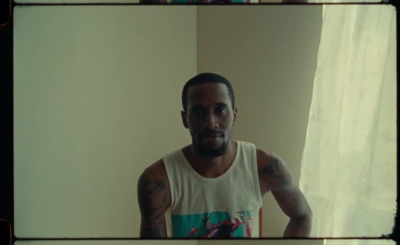 A man is sitting in his room next to a window