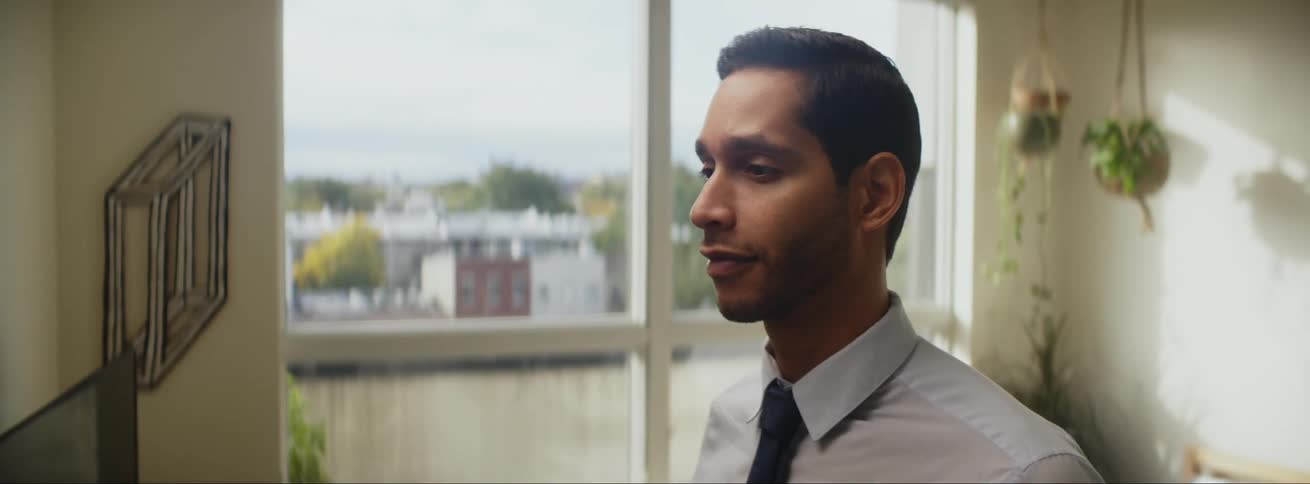 A man is standing indoors and wearing a suit