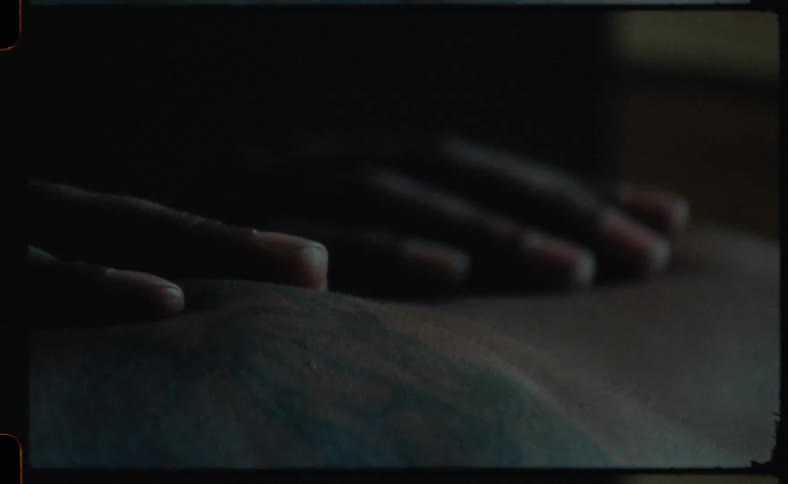 A person runs their hands along the shoulders of a shirtless man