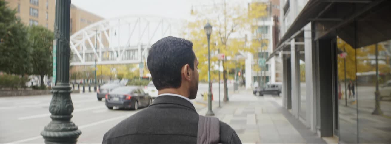 A man is walking through a downtown city in spring