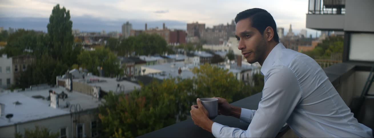 A man is on his balcony drinking coffee