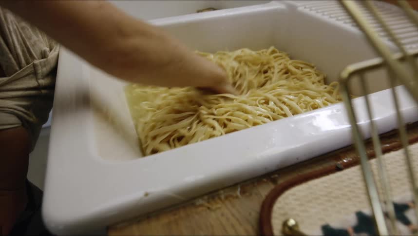 A person mixing pasta in a sink
