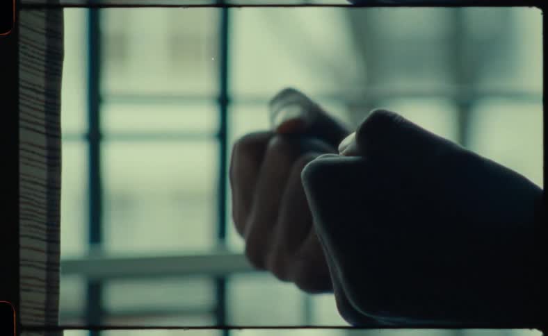 A person in front of a window clenches their hands open and closed