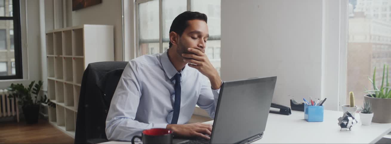 A man is sitting by his laptop and working