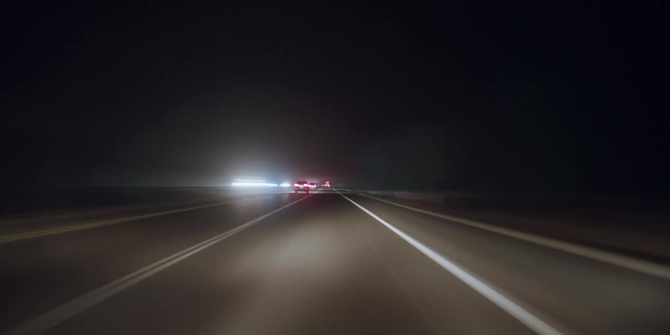 Headlights and tail lights shine as traffic moves on a freeway at night