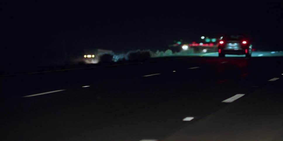 Cars and trucks drive on highway at night