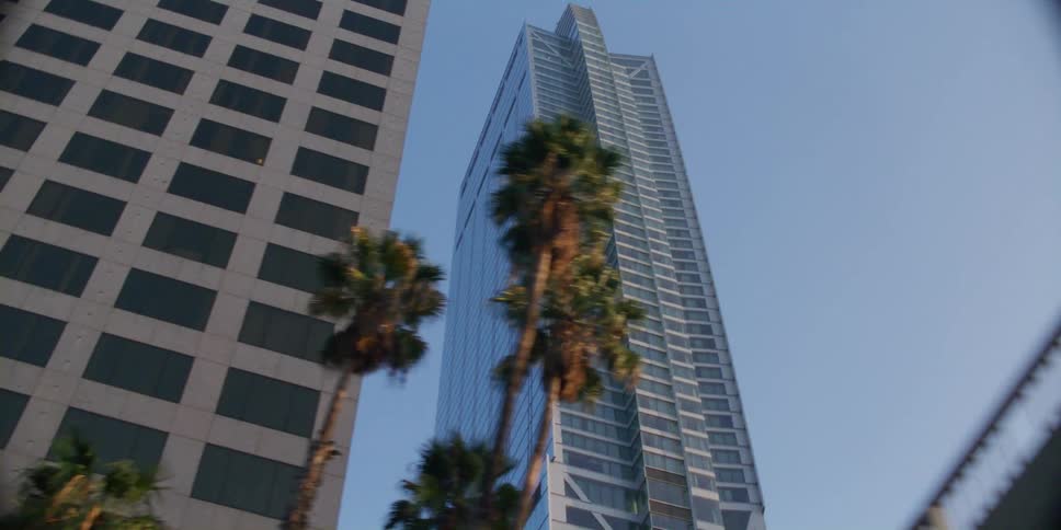 Looking up at skyscrapers in a citys downtown area while passing by in a vehicle during the day
