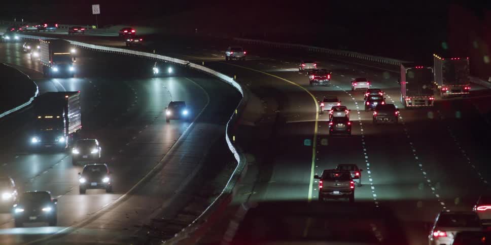 Cars are driving on a highway at night