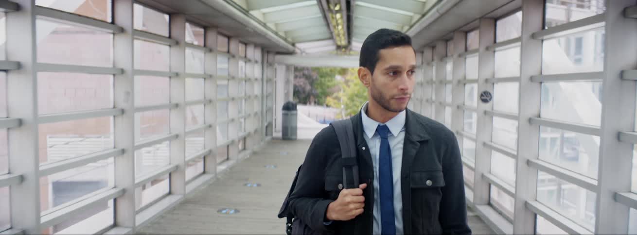 A man carrying a backpack walks down a corridor
